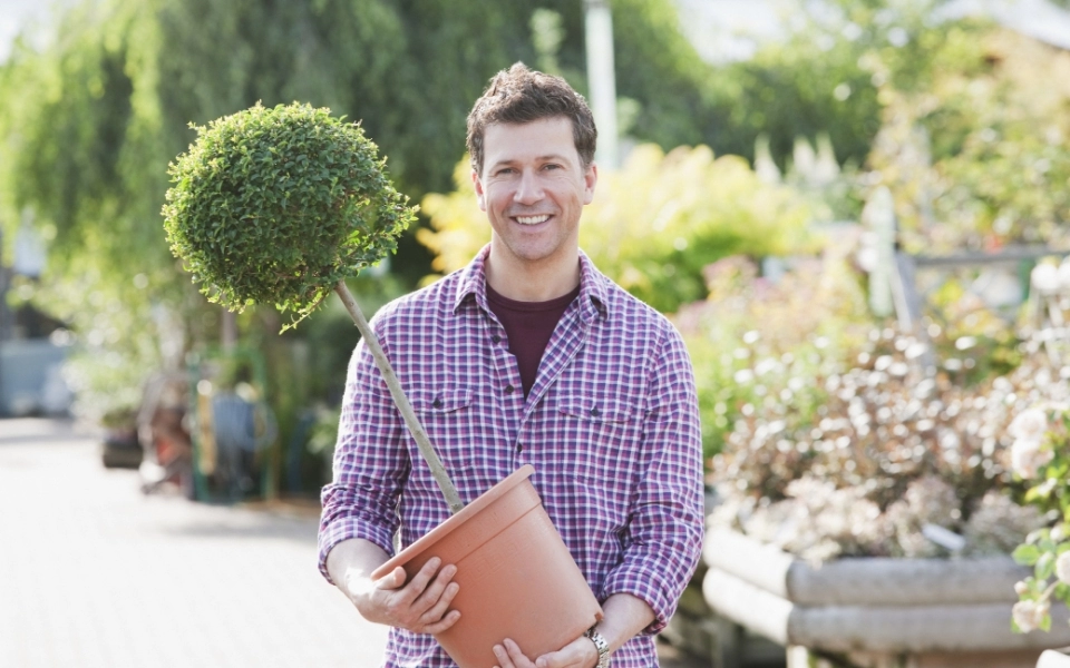 mężczyzna trzymający donicę z rośliną